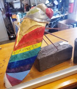 Large rainbow Pride decorative cicada sculpture showcased in a retail space