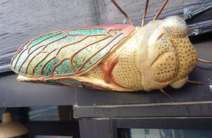 Large gold decorative cicada sculpture mounted on a building exterior.